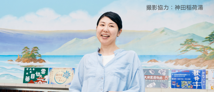 撮影協力：神田稲荷湯 銭湯のペンキ絵の前に立つ田中さん